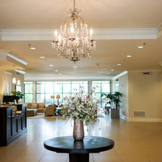 A spacious lobby with a chandelier and floral arrangement on display.
