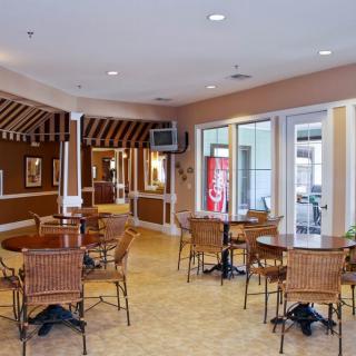 Interior view of a cozy cafe with several tables and chairs, decorated with warm colors and featuring a vending machine and television.
