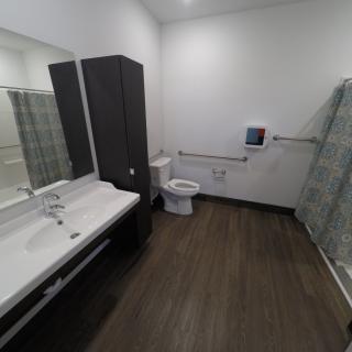 A modern bathroom with a double sink, toilet, and shower.