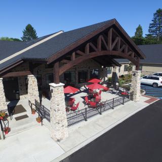 Aerial view of a building with a covered patio featuring red umbrellas and stone pillars.