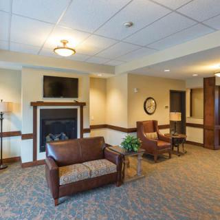A cozy lobby with seating area, featuring a fireplace and television.
