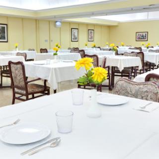 A well-set dining room featuring tables with white tablecloths and vibrant yellow flowers.