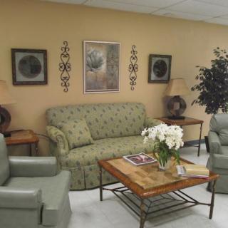 A cozy waiting room with a sofa, chairs, and decorative elements such as artwork and indoor plants.
