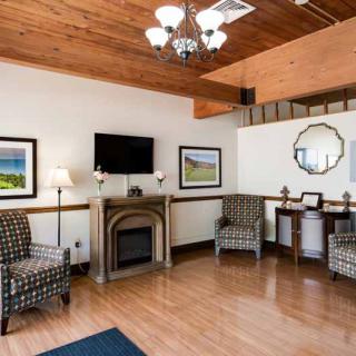 A cozy living room with a wooden ceiling, featuring a fireplace, seating area, and decor elements.