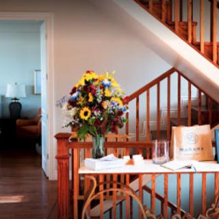 A cozy home interior featuring a wooden staircase and a vase of colorful flowers on a table.