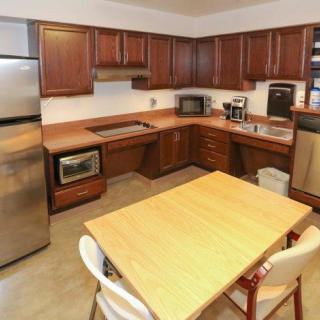 A kitchen with wooden cabinets, a central table, and various appliances including a microwave and refrigerator.