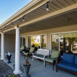 A cozy outdoor patio with comfortable seating and string lights under a covered porch.