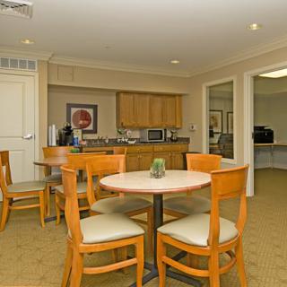 A cozy dining area with wooden furniture and a small kitchenette in the background.