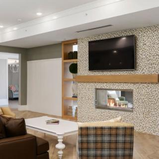 A modern living room with a cozy fireplace, wall-mounted TV, and stylish seating area.