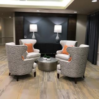 A modern lounge area with four patterned chairs arranged around a round table, accompanied by soft lighting and decorative accents.