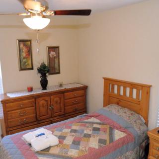 A cozy bedroom featuring a wooden bed with a colorful quilt, a matching dresser, and decorative wall art.