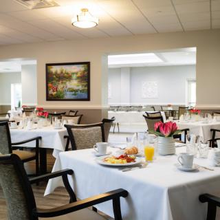 A well-lit dining area with tables elegantly set for breakfast.