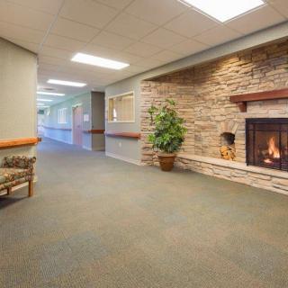A cozy hallway with a stone fireplace, carpeted flooring, and seating area.