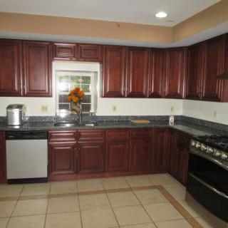 A modern kitchen featuring dark wooden cabinets, sleek countertops, and modern appliances.
