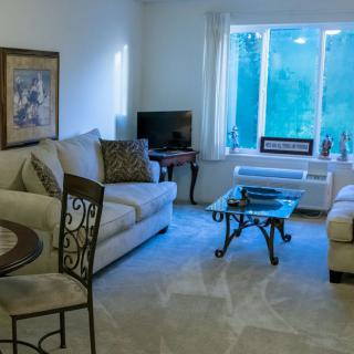 A cozy living room with sofas, a television, and a coffee table in front of a large window.