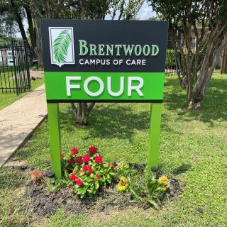 A sign at Brentwood Campus of Care with flowers in front.