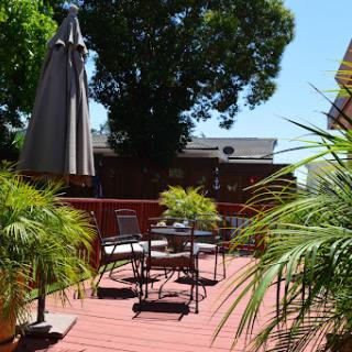 A sunny outdoor patio setup featuring comfortable seating and lush greenery.