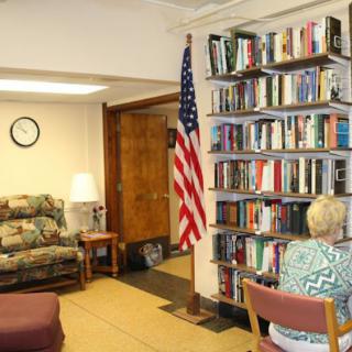 A cozy library corner with a bookshelf, an American flag, and seating areas.