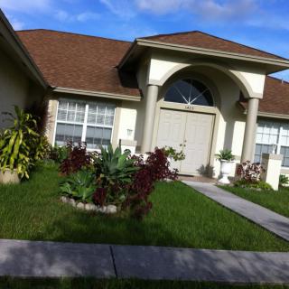 A well-maintained residential house with a lush green lawn and garden in the front.