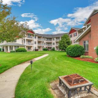 A well-maintained apartment complex with a lush green lawn and a central fire pit.
