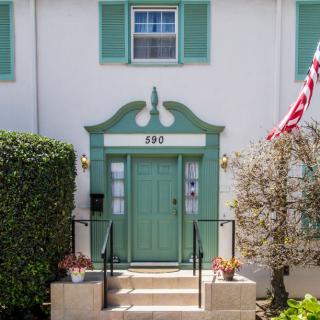 A house entrance with a green door, decorative trim, and an American flag.