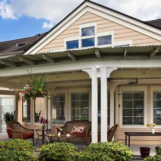 A cozy house with a welcoming porch featuring comfortable outdoor seating and hanging plants.