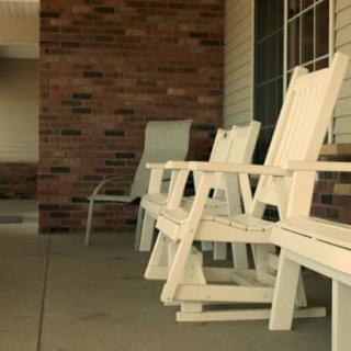 A row of wooden rocking chairs on a porch.
