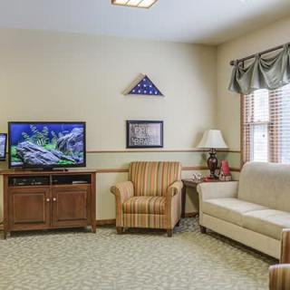 A cozy living room with a sofa, armchair, television, and decorative elements.