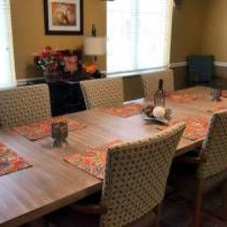 A cozy dining room setup with a wooden table and patterned chairs, adorned with colorful placemats.