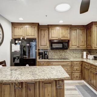 A modern kitchen with wooden cabinets and granite countertops featuring a central island and up-to-date appliances.