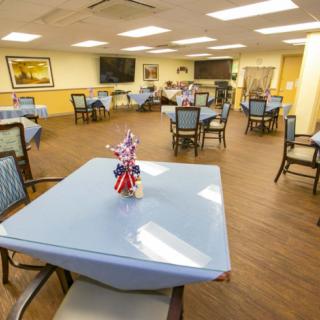 A well-lit dining area with multiple tables and chairs, decorated for a communal gathering.