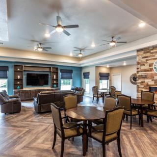 A modern living room featuring a spacious seating area with ceiling fans, a large television, and stylish decor.