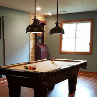 A cozy game room featuring a pool table, stylish lighting, and a vintage arcade machine.