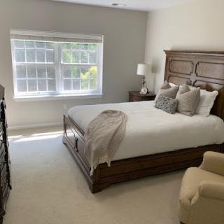A serene and elegantly furnished bedroom with a cozy bed and natural light streaming through the window.
