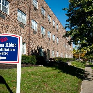 A brick rehabilitation center with a sign outside on a sunny day.