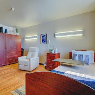 A modern and cozy room featuring a bed, comfortable chair, and elegant lighting.