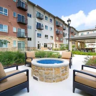 A modern apartment complex featuring a cozy outdoor seating area with a central fire pit.