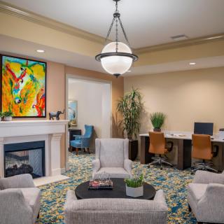 A modern lounge area featuring a fireplace, comfortable seating, colorful artwork, and a computer station.