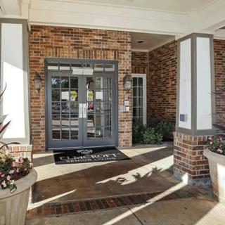 A building entrance featuring double doors surrounded by brick walls, adorned with potted plants.