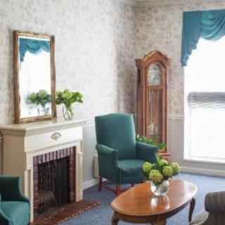 A cozy living room with armchairs, a fireplace, and a grandfather clock.