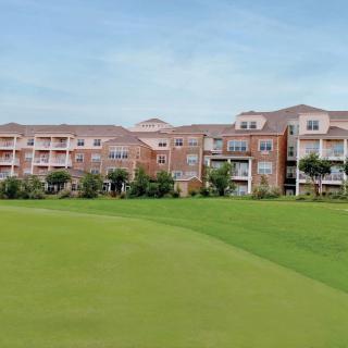 A scenic view of a large building next to a lush golf course under a clear sky.