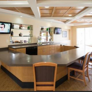 A modern, empty bar with a sleek counter and wooden chairs.