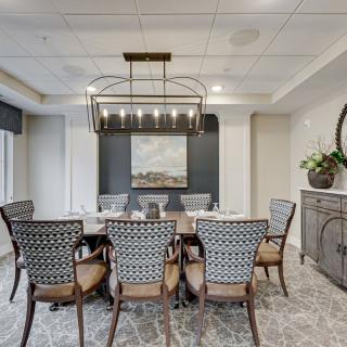 A modern dining room featuring a large table surrounded by elegant chairs, a striking chandelier, and tasteful artwork on the wall.