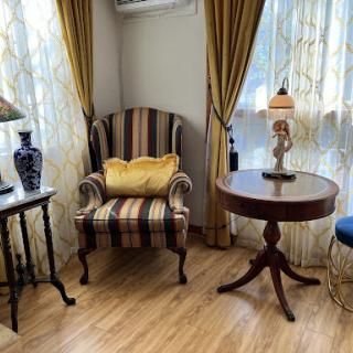 A cozy corner in a living room featuring a striped armchair, elegant drapery, and a decorative lamp.