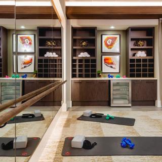 A well-equipped exercise room with yoga mats, yoga blocks, resistance bands, mirrors, and colorful artwork on the shelves.