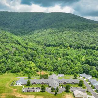 Aerial view of a building complex surrounded by lush green forests with a mountain backdrop.