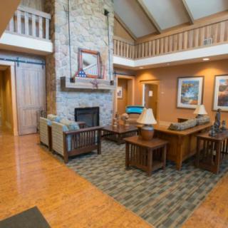 A cozy living room with a stone fireplace, wooden floor, and comfortable furniture.