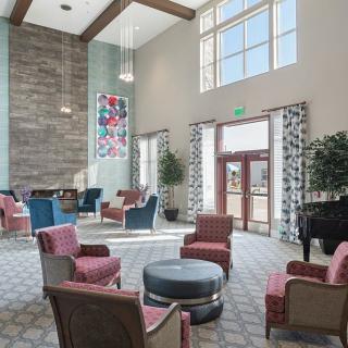 A modern lobby with a comfortable seating area, featuring high ceilings and large windows.