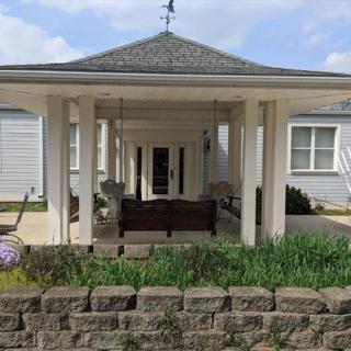 A charming gazebo with a swing surrounded by a garden.
