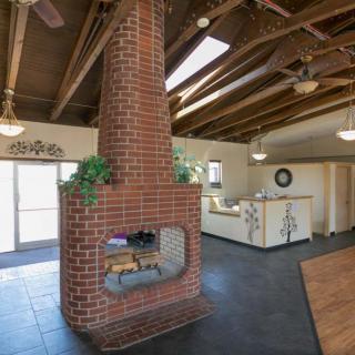 A contemporary open-concept living area featuring a central brick fireplace and exposed wooden beams.